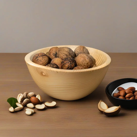 bol frene blanc avec des noix et des feuilles sur une table en bois